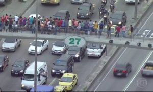 Da passarela da Avenida Brasil, pedestres aguardam a passagem do comboio com Cabral preso - Reprodução de TV 